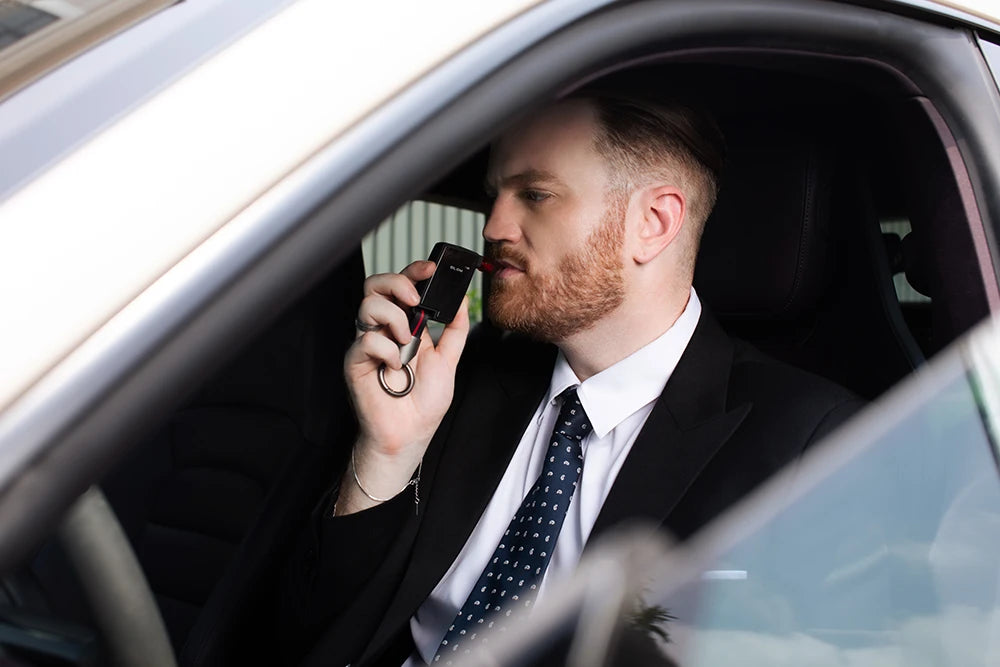 Man blowing into Andatech GT Fuel Cell Breathalyzer in car