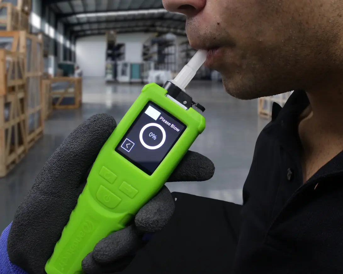 Person blowing into the Andatech Vanguard professional breathalyzer to take an alcohol breath test in an indoor setting