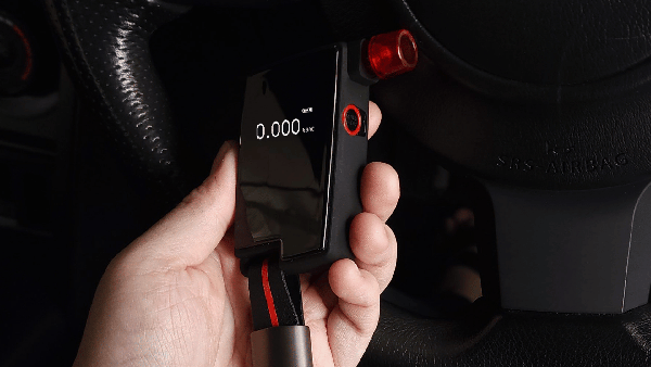 Hand holding Andatech GT Fuel Cell Breathalyzer in car